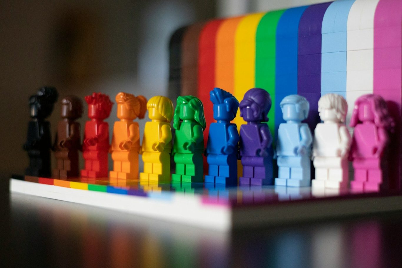 Vielfalt Bunte, LEGO-ähnliche Figuren in einer Reihe vor einem Regenbogen-Hintergrund.